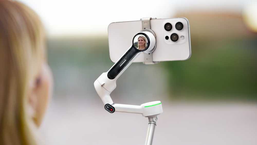 Phone on a robotic arm captures a woman's reflection while she is partially visible in the foreground.