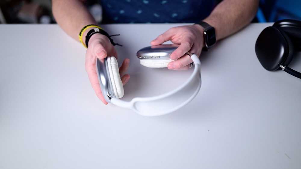 Person holding a pair of silver headphones.