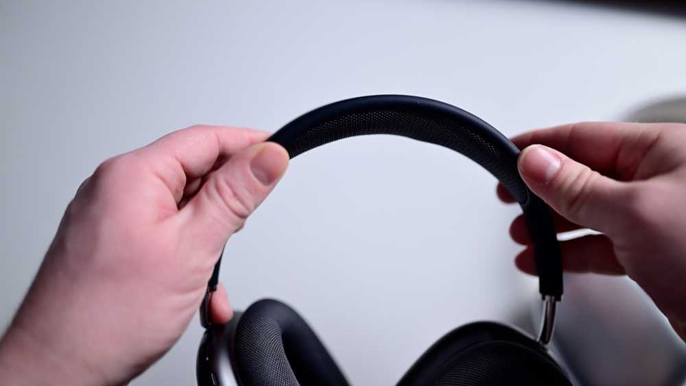 Hands holding black over-ear headphones.