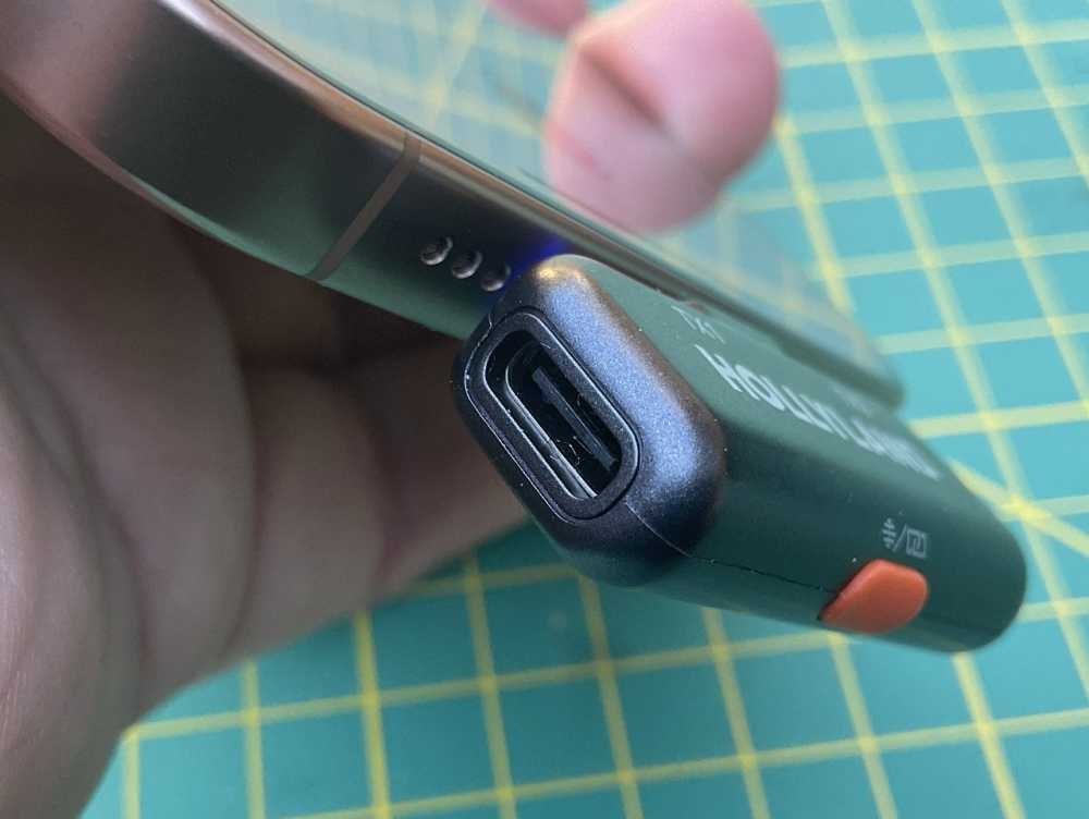 一只手拿着一个黑色的 USB-C 闪存驱动器连接到智能手机，背景是绿色的切割垫。