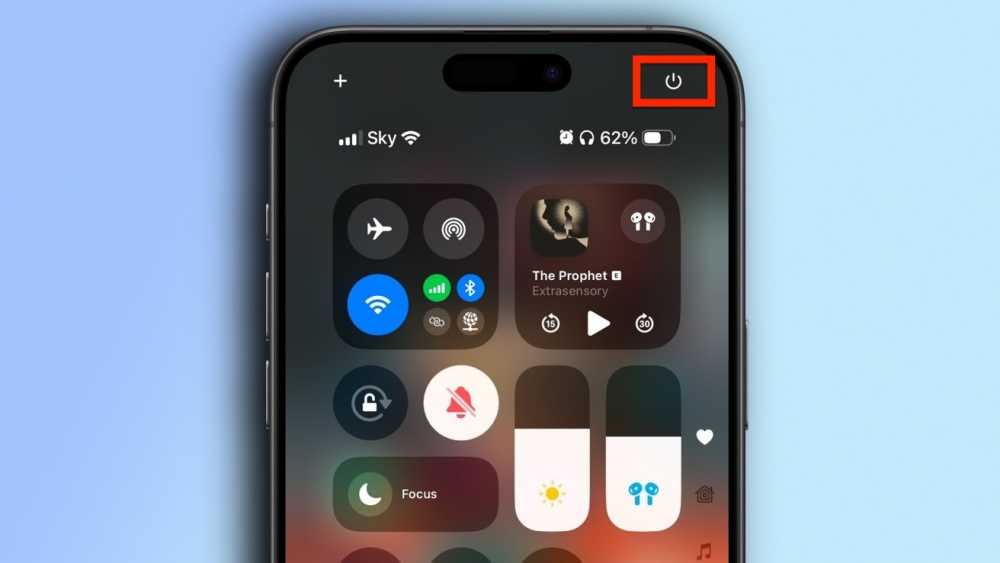 Smartphone screen showing control center with airplane mode, Wi-Fi, Bluetooth icons, music player, and power button highlighted in red at the top right with a blue gradient background.