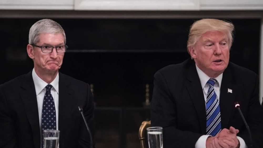 Two men in suits sitting at a table, one appears thoughtful, the other is speaking.