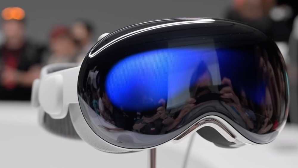 Futuristic virtual reality 头显 with a reflective, sleek visor displaying a blue hue. Background shows blurred figures observing the 头显.