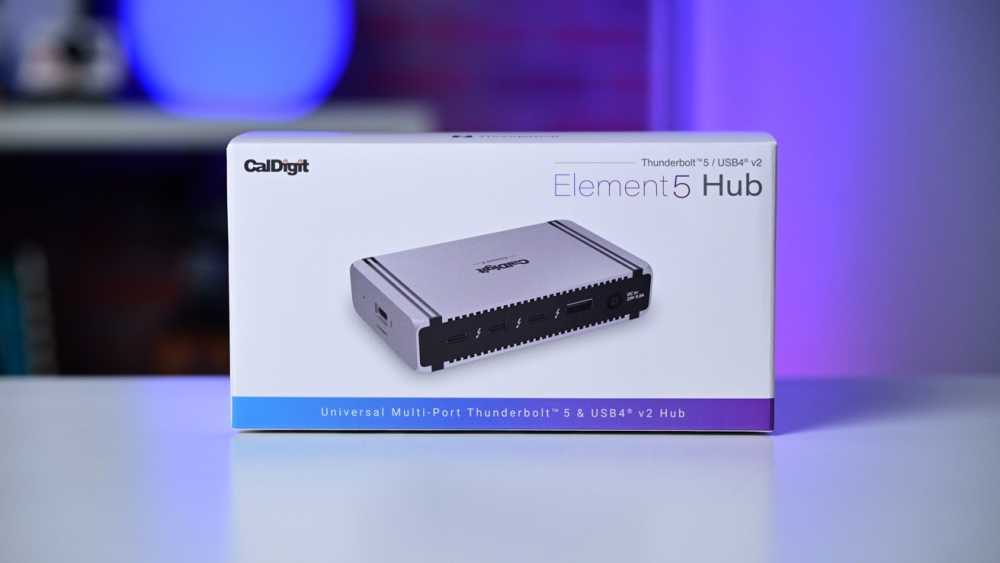 White box displaying a CalDigit Element Hub, featuring multiple ports. Background blends blurred purple and blue tones.