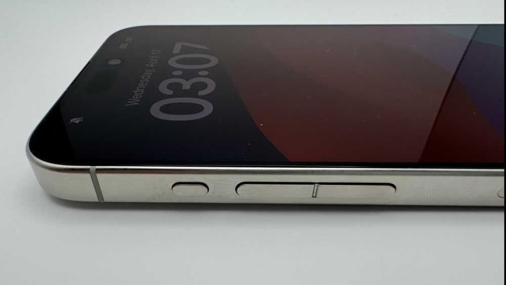 Smartphone on a white surface displaying time 03:07, April 17, with a metal edge showing side buttons.
