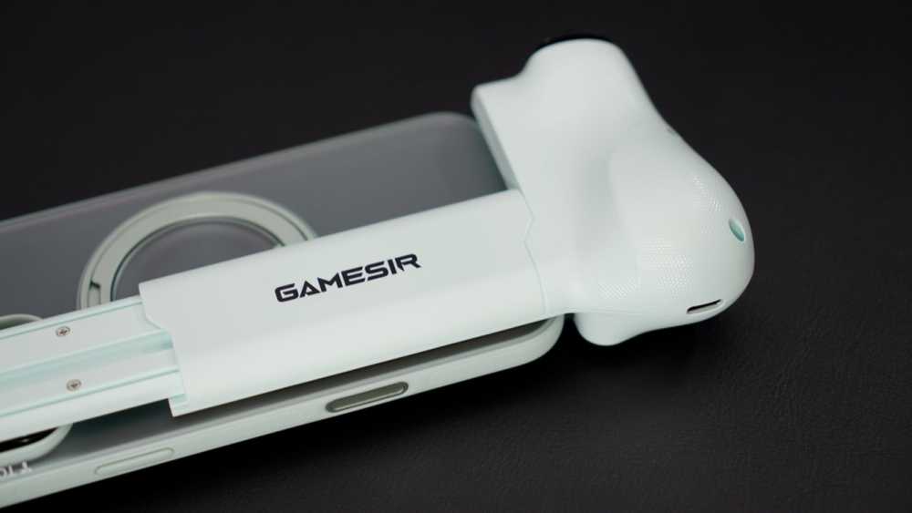 浅绿色 GameSir 手柄部分连接到放在黑色表面上的智能手机。