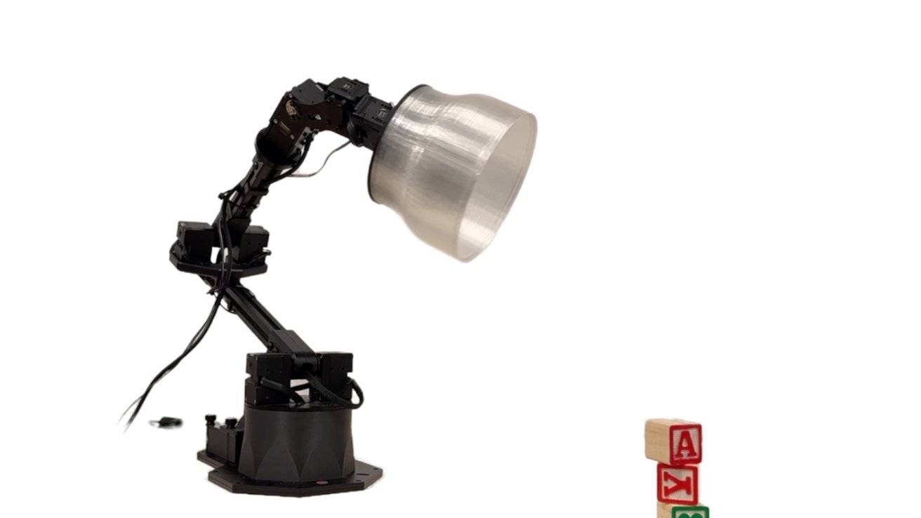 带有大型锥形灯具的机械臂在白色背景上伸向三个堆叠的字母积木。