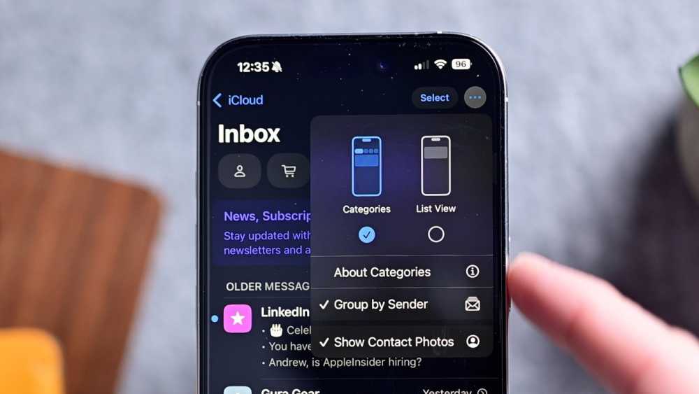 iPhone 在灰色桌面上显示电子邮件应用程序，其中包含一个弹出菜单，显示各种选项，包括显示或隐藏联系人照片的切换开关