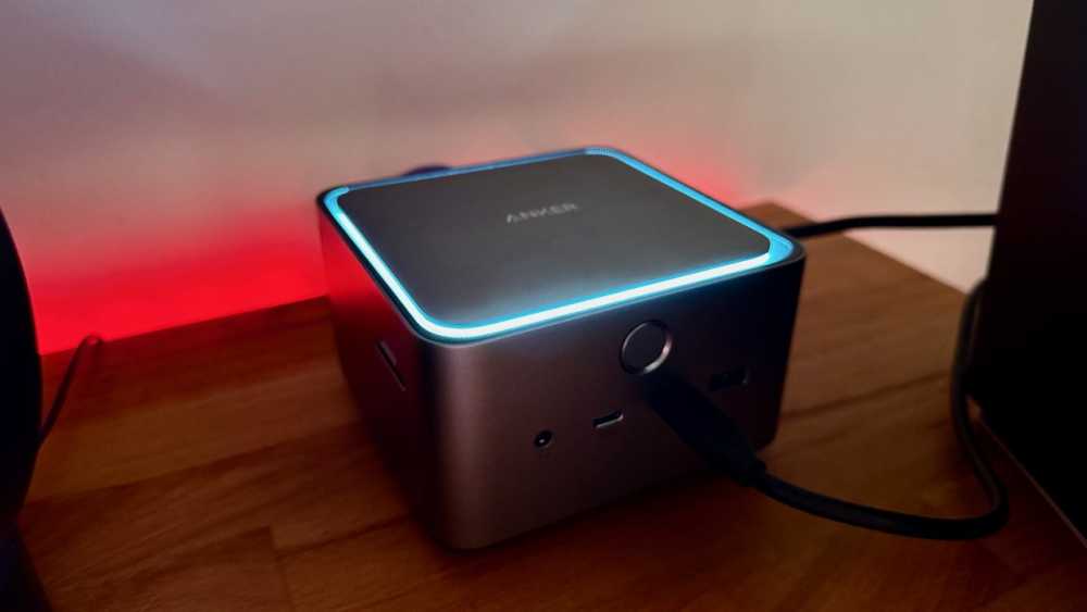 Anker 扩展坞顶部发出蓝色光，放置在木质表面上。 它有多个端口，并通过黑色电缆连接。