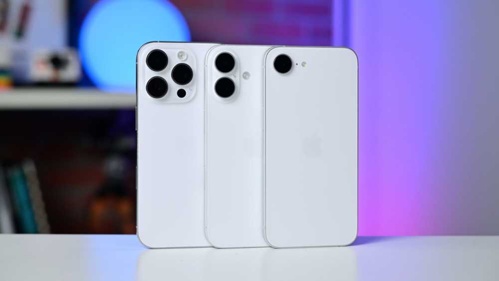 Three white smartphones with different sizes and camera designs stand upright on a surface, set against a blurred background with blue and purple lighting.
