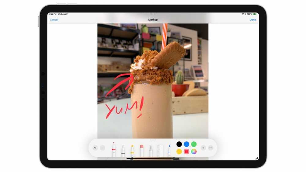 A milkshake topped with whipped cream, cookie crumbs, and a whole cookie, with 'Yum!' written in red on a tablet screen.