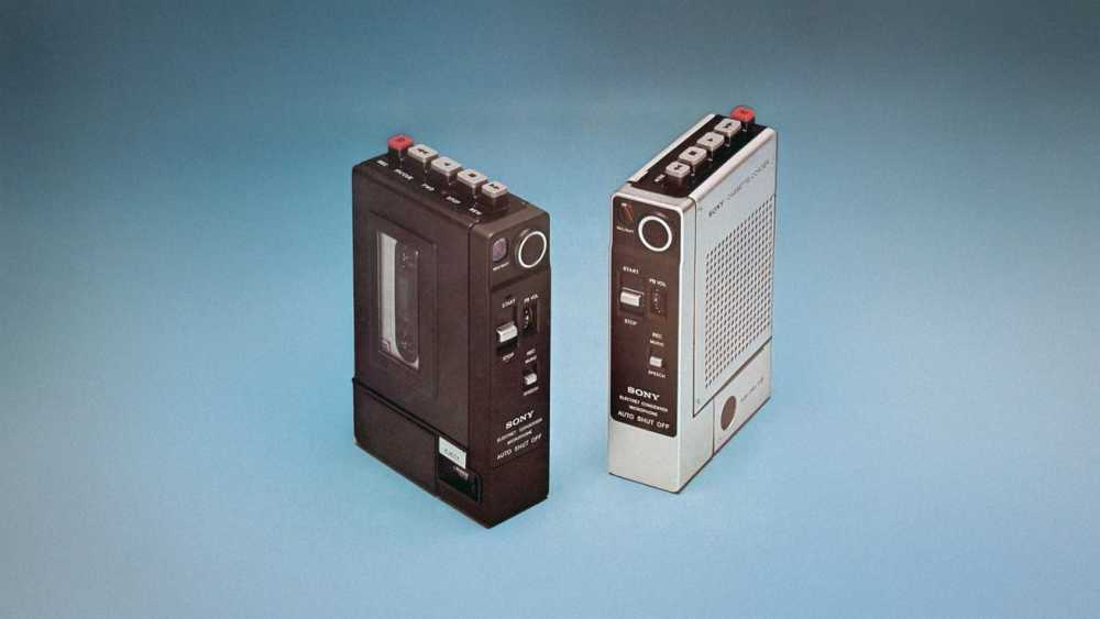 Two vintage portable cassette recorders, one black and the other white, with buttons and switches, displayed against a blue gradient background.
