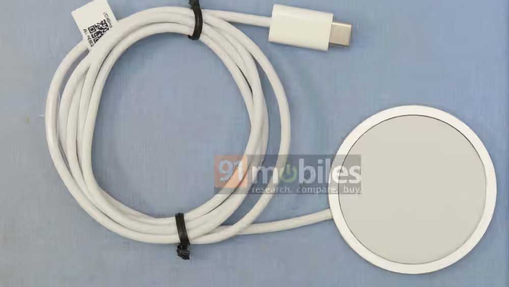 White coiled charging cable with USB-C connector and magnetic round charging pad on a blue surface. Branding watermarked over the charging pad.
