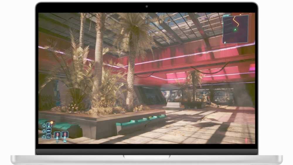 Laptop screen displaying a virtual city plaza with palm trees, vibrant red and pink lighting, and modern architectural elements reflecting a futuristic environment.