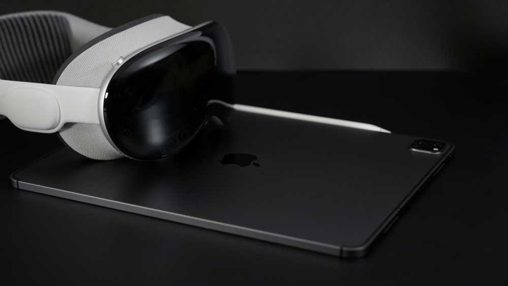 VR 头显 and stylus resting on a sleek tablet with an Apple logo, all on a dark surface.
