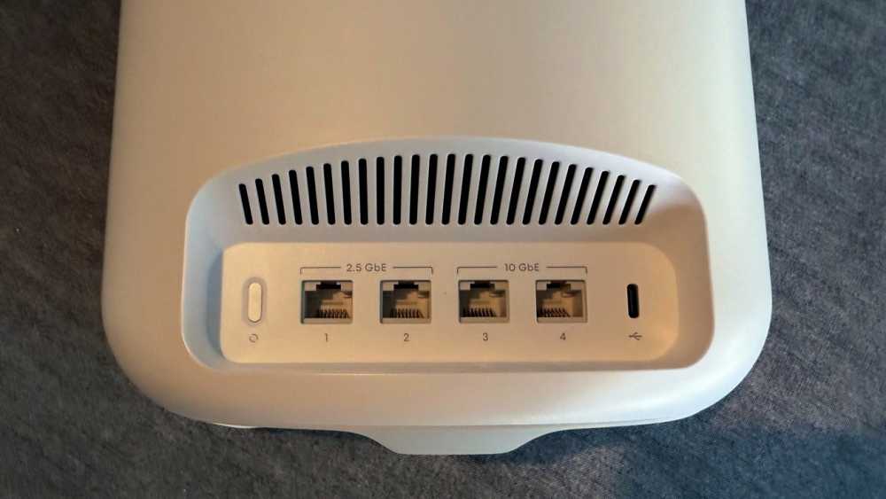 White electronic device with ventilation slits, four Ethernet ports labeled 2.5 GbE and 10 GbE, and one USB-C port against a dark surface.