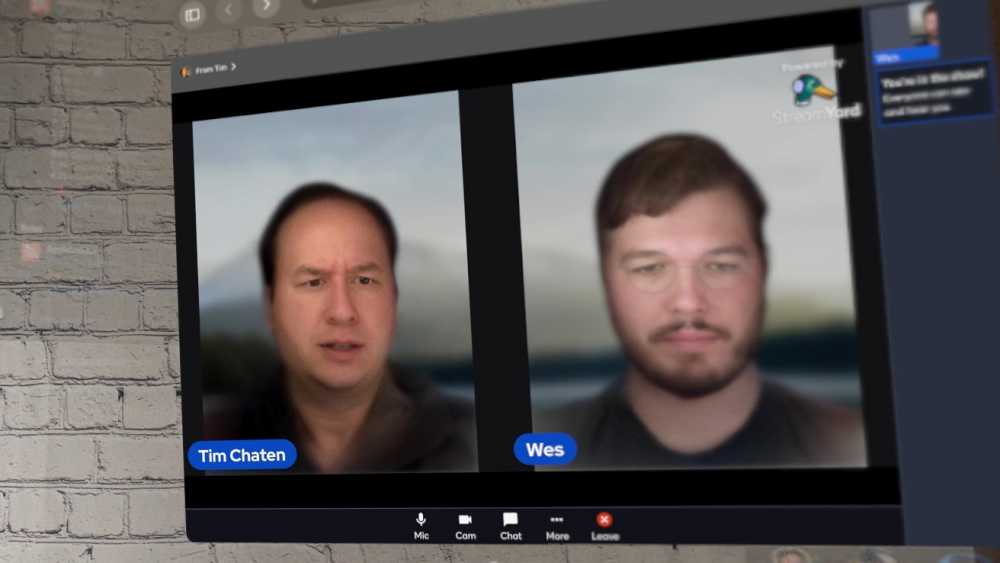 Two men are seen in a blurred video call on a screen against a brick wall.