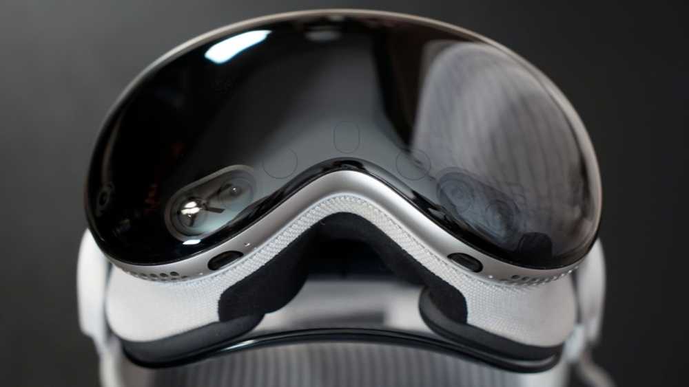 Sleek, reflective black visor on white virtual reality 头显 with smooth curves and vents, set against a dark background.