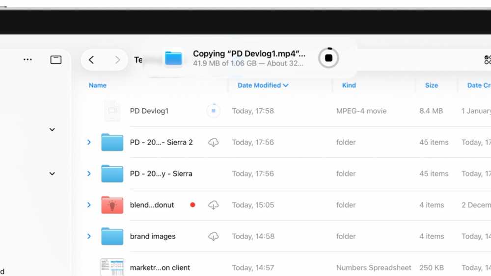 Mac 上的文件目录显示文件夹和文件。进度条指示“PD Devlog1.mp4”正在复制。其他文件夹和文件以及详细信息（如大小和修改日期）也已列出。