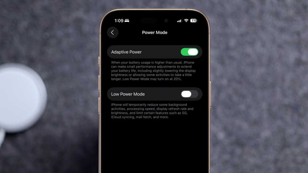 Smartphone screen displaying power mode settings with options for Adaptive Power and Low Power Mode against a blurred background.