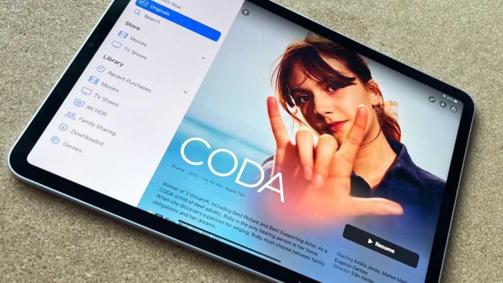 Tablet displaying movie library interface and 'CODA' movie poster with a woman signing in the foreground.