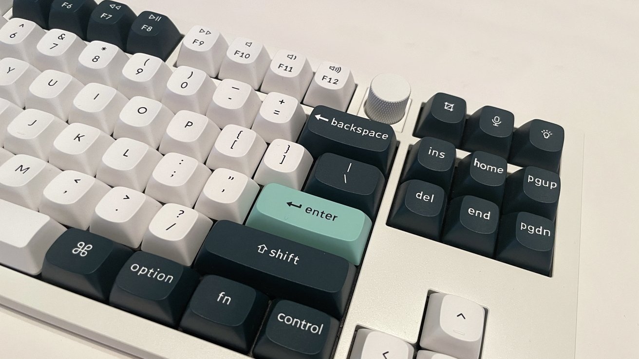 Keyboard with white and dark keys, some labeled backspace and enter. Contains a control knob and function keys.