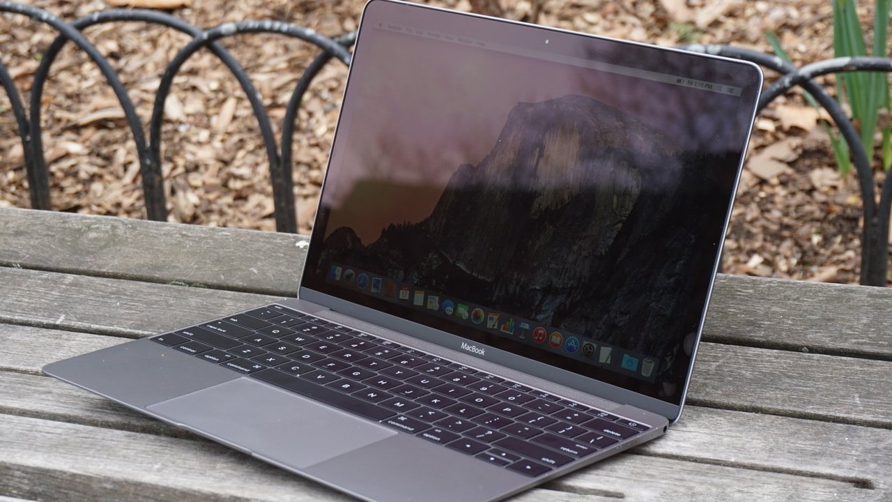 Laptop with a reflective screen on a wooden bench, displaying a scenic desktop background, surrounded by a garden setting with dirt, leaves, and metal railings.