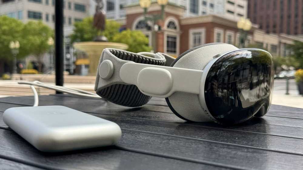 VR 头显 and charging pack resting on outdoor table in urban setting with blurred buildings and greenery in the background.
