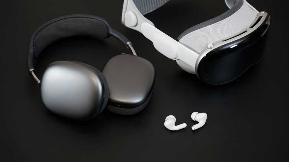 Grey over-ear headphones, white VR 头显 with dark visor, and white wireless earbuds on a black surface.