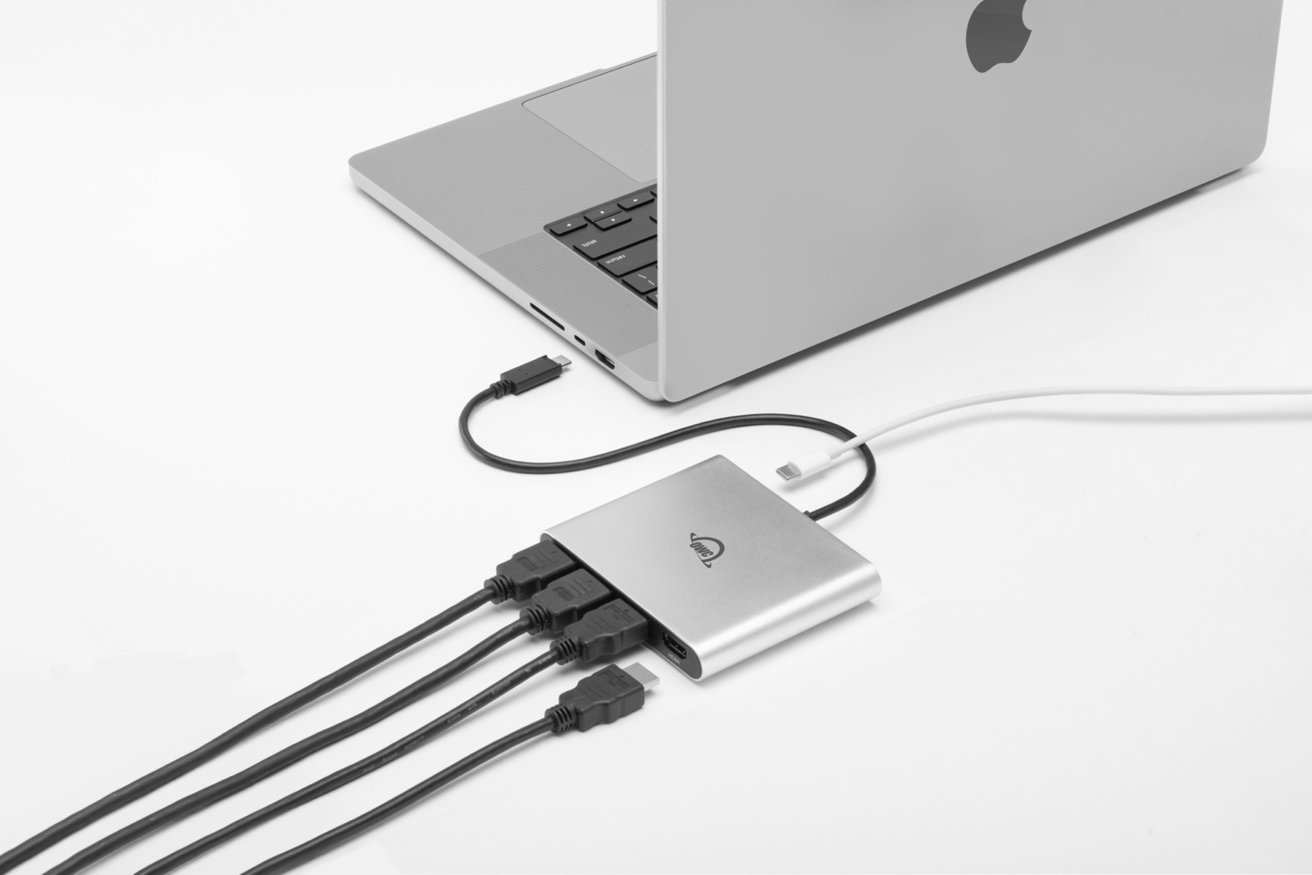 Silver laptop connected to a sleek silver hub with four plugged-in cables on a white background.