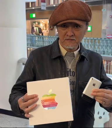 老人手持第一代iPhone在北京Apple荟聚店前合影