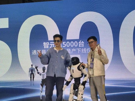 黄晓明与智元第5000台人型机器人同步比心：我很喜欢它的黄色鞋子  因为我姓黄